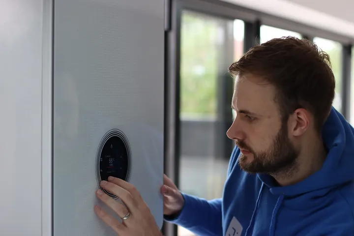 Engineer adjusting the control dial on a modern wall-hung combi boiler