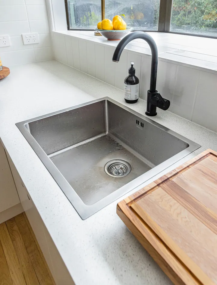 Stainless steel kitchen sink with a black tap and open waste