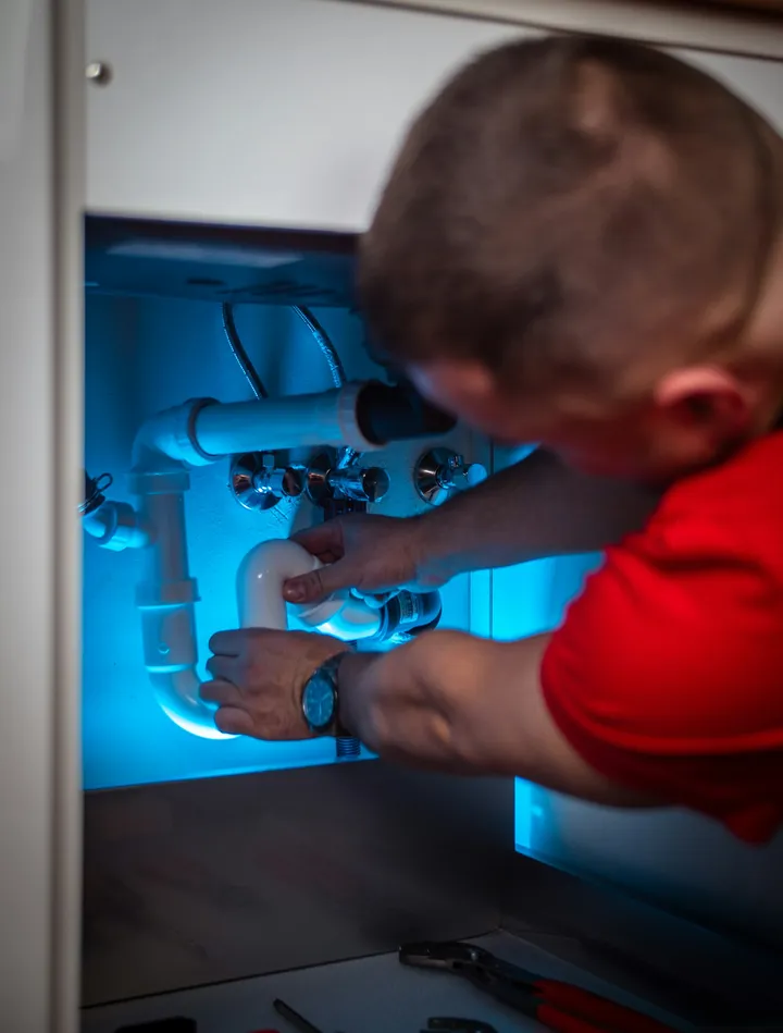 Plumber assembling a waste trap under a kitchen sink