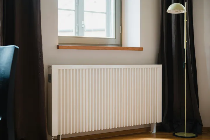White panel radiator fitted under a window in a home